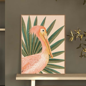 May include: A pink and orange pelican with a long beak stands in front of a green palm leaf background. The pelican is facing the right side of the image. The background is a light peach color.
