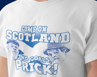 Puede incluir: Camiseta blanca con un estampado gráfico azul y blanco que dice "Come on Scotland Two Goals Prick!" con dos caras de dibujos animados de hombres con sombreros.
