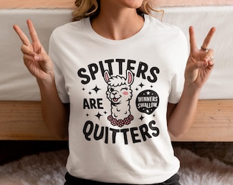Op de afbeelding: Wit T-shirt met de tekst "Spitters Are Quitters" en een cartoon lama-afbeelding. De lama heeft een roze bloemenketting en de tekst "Winners Swallow" in een tekstballon. Een casual stijl.