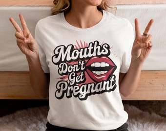 May include: White t-shirt with the text "Mouths Don't Get Pregnant" in a black and red design. The graphic includes a pair of red lips. The shirt is a casual wear item.