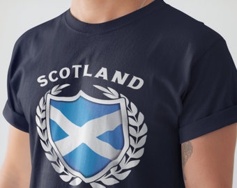 May include: A navy blue t-shirt with a white shield featuring the Scottish flag and the word "SCOTLAND" above it.