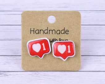 May include: A pair of handmade earrings featuring a red and white heart icon with the number "1" inside. The earrings are displayed on a brown card with the text "Handmade with love".