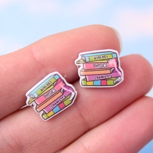 May include: A pair of stud earrings featuring a stack of colourful books with the titles "Biology", "Physics", and "Chemistry".
