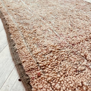 May include: A close-up of a beige and brown shag rug with a textured surface. The rug has a subtle striped pattern.