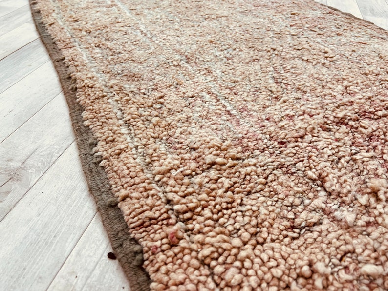 May include: A close-up of a beige and brown shag rug with a textured surface. The rug has a subtle striped pattern.