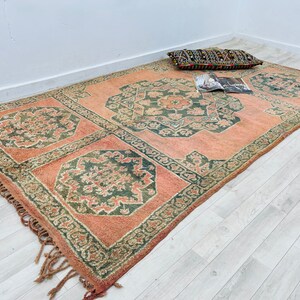 May include: A pink and green patterned rug with fringed edges. The rug has a traditional design with intricate details.