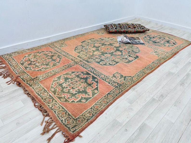 May include: A pink and green patterned rug with fringed edges. The rug has a traditional design with intricate details.