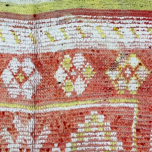 Puede incluir: Primer plano de una alfombra roja, blanca y amarilla con un dise&ntilde;o tejido texturizado. La alfombra tiene un patr&oacute;n repetitivo de flores.