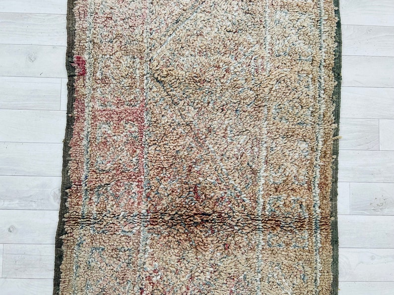 May include: A vintage rug with a faded, intricate pattern in shades of beige, brown, and red. The rug has a worn, distressed look, adding to its character.