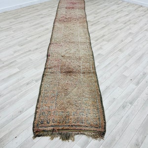 May include: A long, rectangular rug with a faded, multi-colored pattern. The rug has a fringe on both ends and is made of a soft, woven material.