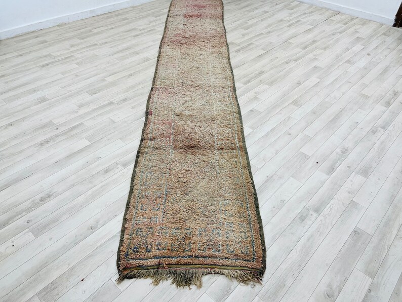 May include: A long, rectangular rug with a faded, multi-colored pattern. The rug has a fringe on both ends and is made of a soft, woven material.