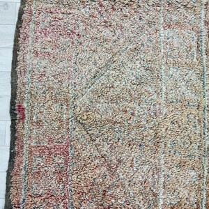 May include: A vintage rug with a faded, geometric pattern in shades of beige, brown, and pink. The rug has a distressed, worn look, adding to its unique character.