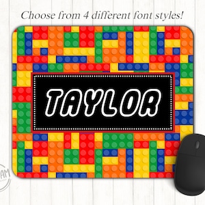 May include: A rectangular mousepad with a colorful brick pattern in red, orange, yellow, green, and blue. The name "TAYLOR" is displayed in white block letters on a black rectangle. A black computer mouse is on the right. Text at the top says "Choose from 4 different font styles!"