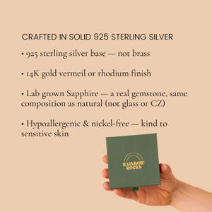 May include: A square dark green jewelry box with the gold text RAINBOW ROCKS and a rainbow icon. Text lists product details: CRAFTED IN SOLID 925 STERLING SILVER, 925 sterling silver base, 14K gold vermeil or rhodium finish, Lab grown Sapphire, Hypoallergenic & nickel-free.