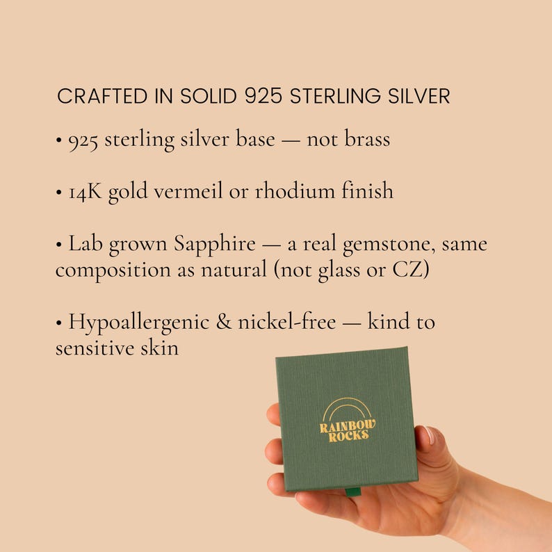 May include: A square dark green jewelry box with the gold text RAINBOW ROCKS and a rainbow icon. Text lists product details: CRAFTED IN SOLID 925 STERLING SILVER, 925 sterling silver base, 14K gold vermeil or rhodium finish, Lab grown Sapphire, Hypoallergenic & nickel-free.