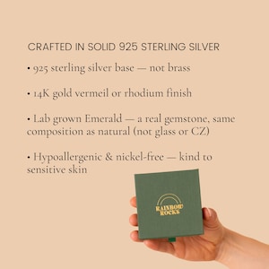 K&ouml;nnte beinhalten: Eine quadratische dunkelgr&uuml;ne Schmuckschatulle mit dem goldenen Text RAINBOW ROCKS und einem Halbkreis-Symbol. Der Text dar&uuml;ber listet Produktdetails auf: CRAFTED IN SOLID 925 STERLING SILVER, 925er Sterlingsilber-Basis, 14K Gold-Vermeil- oder Rhodium-Finish, im Labor gez&uuml;chteter Smaragd, hypoallergen und nickelfrei.