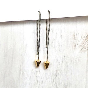 May include: A pair of gold and silver chain earrings with a pointed gold tip at the end of each chain.