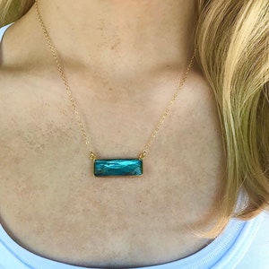 May include: A gold chain necklace with a rectangular blue-green gemstone pendant.