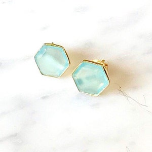 May include: A pair of gold stud earrings with hexagonal light blue gemstones.