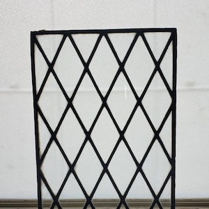 May include: A black metal windowpane with a diamond pattern. The windowpane is made of clear glass and is set in a black metal frame.