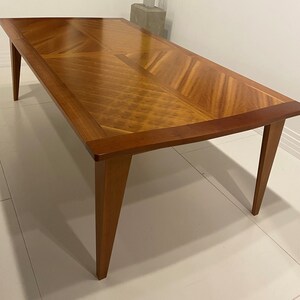 May include: A rectangular wooden dining table with a chevron pattern inlay. The table has a dark wood finish and four legs.