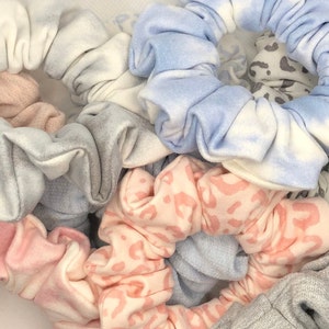 Peut inclure: Une collection de chouchous colorés dans différents motifs, notamment tie-dye, léopard et unis. Les chouchous sont faits d'un tissu doux et extensible et sont parfaits pour maintenir les cheveux en place.