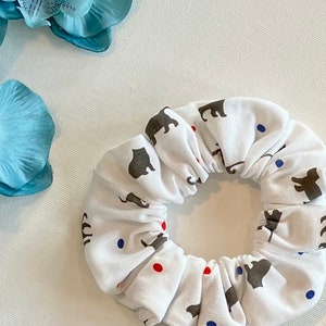 May include: White scrunchie with a pattern of small gray animal silhouettes and red and blue dots.
