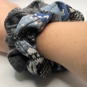 May include: A gray and blue patterned scrunchie made of fabric.