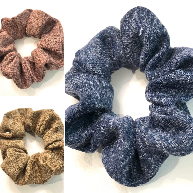 May include: Three scrunchies in different colors: brown, beige, and blue. The scrunchies are made of a soft, stretchy fabric.