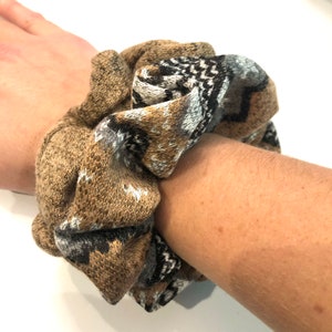 May include: A brown and gray patterned scrunchie made of knitted fabric.