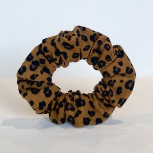 May include: A brown and black leopard print scrunchie for hair.