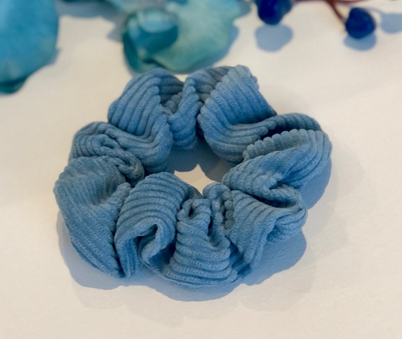 Puede incluir: Un scrunchie para el pelo de color azul de pana. El scrunchie est&aacute; hecho de un tejido suave y texturizado, ideal para sujetar el pelo.