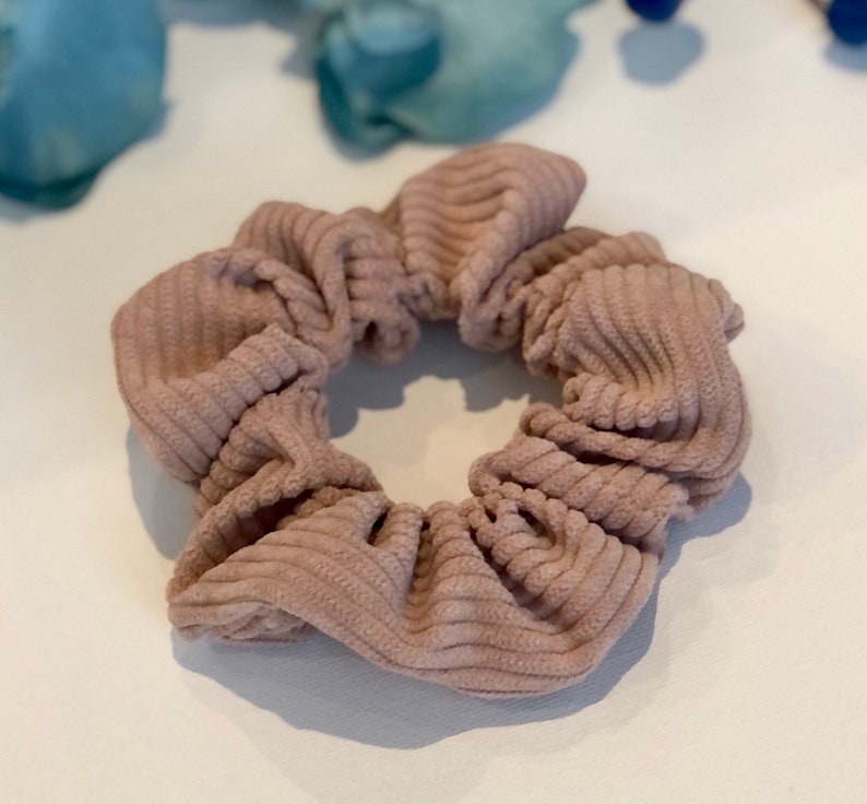 Puede incluir: Una scrunchie para el pelo de color marr&oacute;n claro de pana.