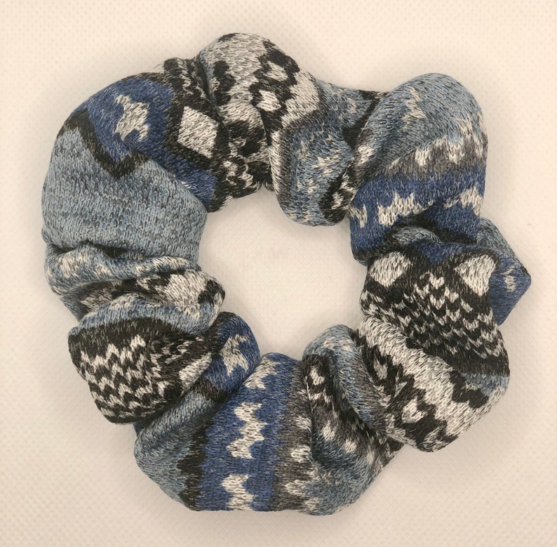 May include: A blue, black, and white patterned scrunchie made of soft, knitted fabric.