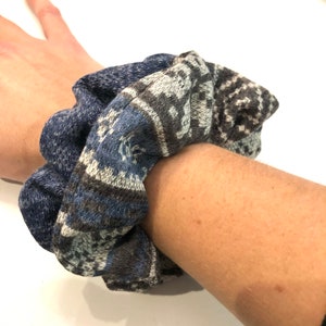 May include: A blue and gray patterned scrunchie made of fabric.