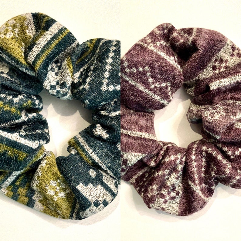 May include: Two patterned scrunchies, one in green, white, and gold, and the other in purple, white, and gray.