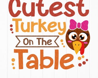 May include: A Thanksgiving-themed graphic design with the text "Cutest Turkey On The Table" in orange and brown lettering. A cartoon turkey with a pink bow is featured in the center of the design.