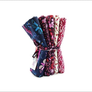 May include: A bundle of six fabric squares featuring floral and butterfly patterns in shades of pink, red, white, and blue. The fabric is tied together with a ribbon.