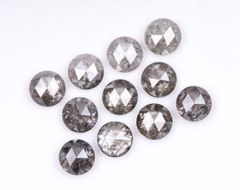 May include: A collection of ten round, faceted, grey diamonds. The diamonds are arranged in a loose, asymmetrical pattern on a white background.