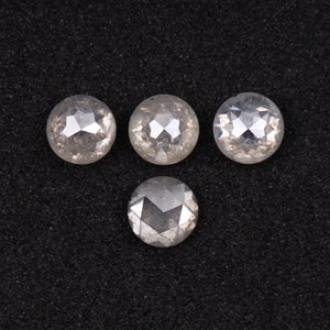 Puede incluir: Cuatro piedras preciosas redondas, facetadas, transparentes, blancas, en forma de diamante sobre un fondo negro.