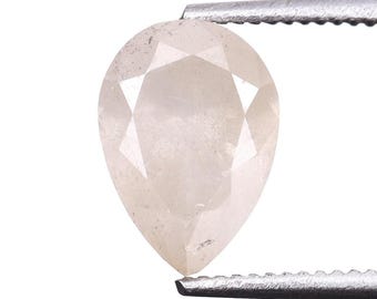 May include: A light-coloured, pear-shaped gemstone held by tweezers. The gem has multiple facets, creating a sparkling effect. The stone appears to be a diamond or similar precious stone, suitable for jewellery.