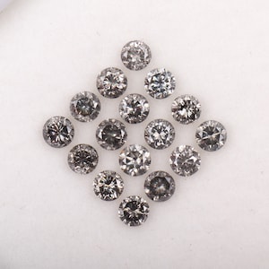 Puede incluir: Una colección de 15 diamantes redondos grises dispuestos en forma de diamante sobre una superficie blanca.