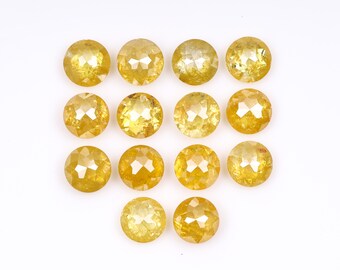 May include: A collection of 12 round, faceted, yellow gemstones. The gemstones are arranged in a heart shape on a white background.