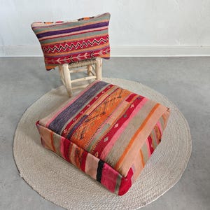 May include: A rectangular throw cushion with horizontal stripes in purple, red, orange, and green, resting on a small wooden stool, paired with a large, square floor cushion featuring matching multi-coloured striped fabric patterns.
