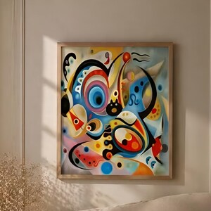 May include: Abstract artwork in a wooden frame. The painting displays a colourful arrangement of shapes and forms in blue, red, yellow, and black. The framed art hangs above a bed with neutral-toned bedding.