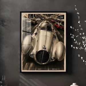May include: Framed vintage racing car poster. The artwork features a silver race car speeding down a city street, with other cars in the background. The poster is in a black frame and hangs on a dark gray wall.