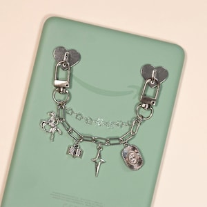 May include: A silver-toned metal chain accessory featuring two heart-shaped adhesive attachments, a delicate star-link chain, and a thicker link chain adorned with charms including a horse, an open book, a four-pointed star, and an oval medallion.