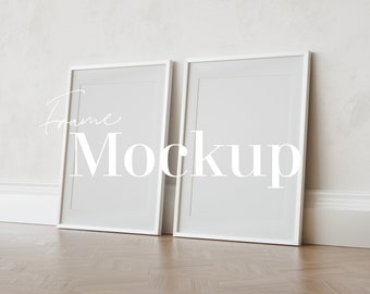 May include: Two white rectangular picture frames leaning against a light-colored wall. The frames have a thin white border and a large white space for artwork or photos. The text "Frame Mockup" is overlaid on the frames.
