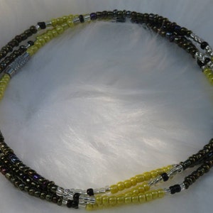 May include: A multi-strand beaded necklace with yellow, brown, black, and silver beads.