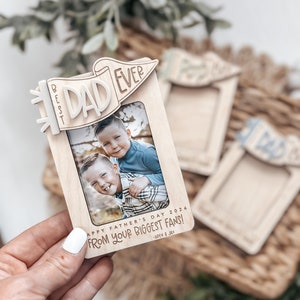 May include: Wooden photo frame with a banner that says "Best Dad Ever". The frame has a photo of two boys and the text "Happy Father's Day 2024 From Your Biggest Fans! - Aiden & Jax"